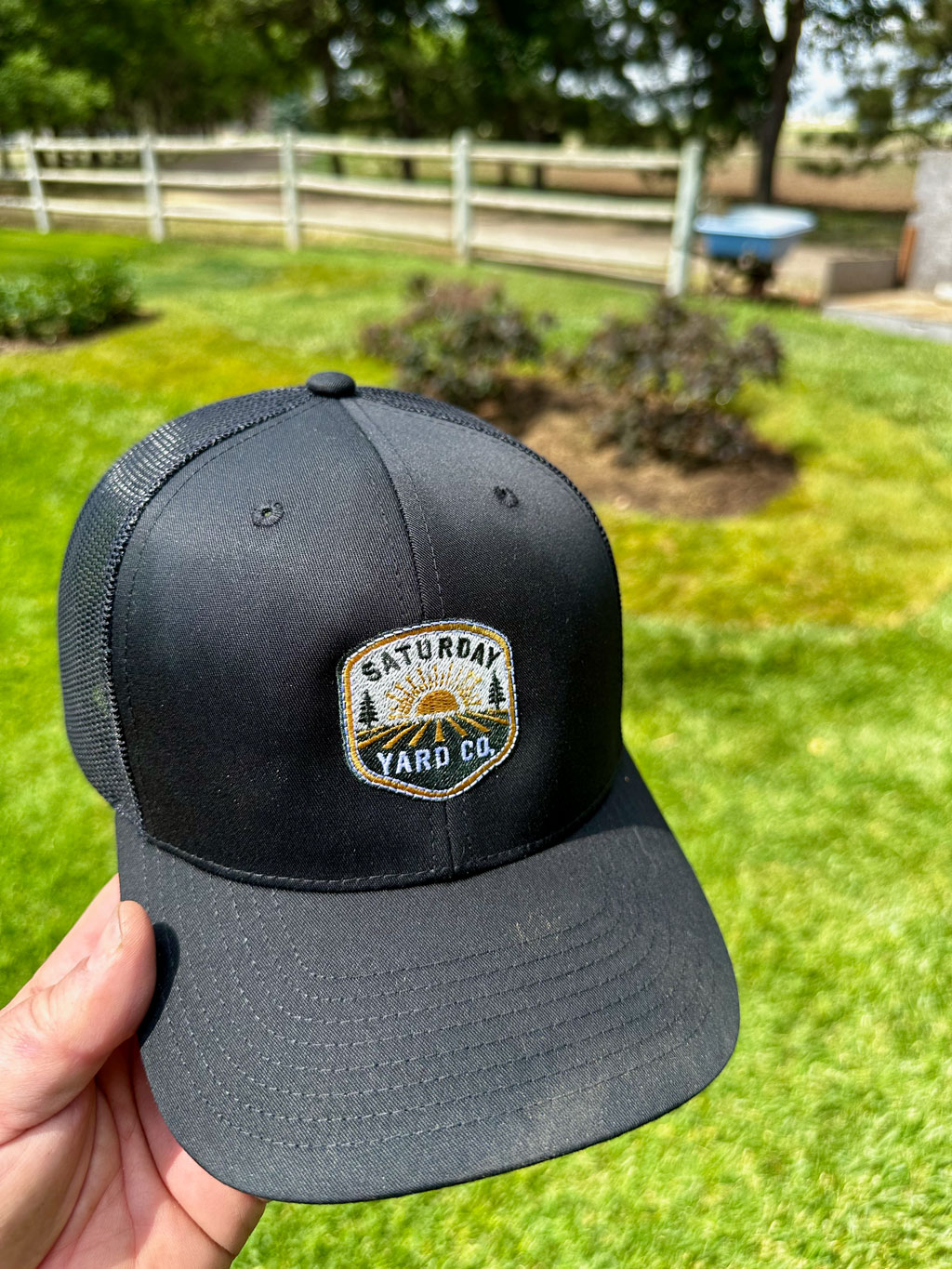Saturday Yard Co. trucker hat against the finished Longmont property lawn
